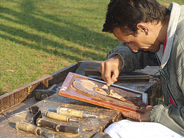 Artesão entalhando em baixo relevo