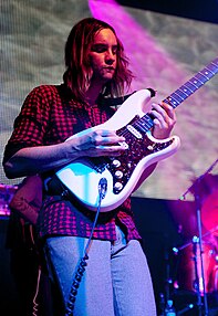 Kevin Parker playing the guitar during a concert.