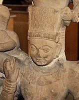 Vasudeva with ornate crown and flower necklace, making the Abhaya Mudra