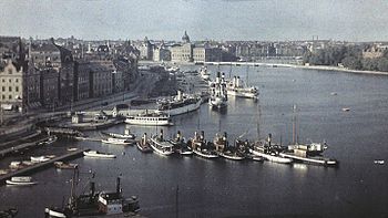 En vy från Mosebacke över Saltsjön mot norr. Bilden till vänster fotograferades av Gustaf Cronquist 1928 på en autochromplåt från sin bostad högt över Stadsgården, där KF sedermera byggde sina kontorshus. Från denna utsökta position dokumenterade Cronquist Stockholms liv och trafik under många år. Högra bilden visar samma vy i mars 2009 över Gamla stan, Blasieholmen och Skeppsholmen.