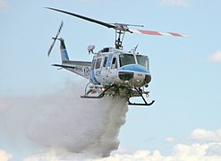 Bell 205 de un departamento de incendios de California lanzando agua sobre un fuego.