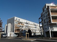 Phot de deux grands immeubles, sur fond de ciel bleu.