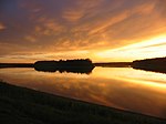 Brilliant sunset over a wide river flowing through woods