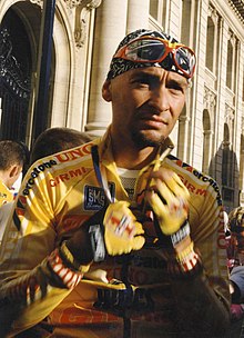 A cyclist wearing a yellow jersey while in the process of unzipping his jersey.