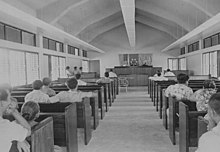 Intérieur d'un bâtiment avec deux allées de bancs aboutissant aux bureaux des juges