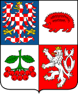 Blason à quatre quarts portant en haut à gauche une aigle héraldique carrelée argent-gueules (symbole morave), en haut à droite un hérisson de gueules stylisé sur fond argent, en bas à gauche une grappe de groseilles sur fond argent, et en bas à droite le lion rampant argent couronné d'or sur fond de gueules (symbole de la Bohême)