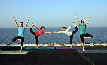 A US Navy yoga display on the flight deck of USS George H.W. Bush, using Vrikshasana and Natarajasana, 2014