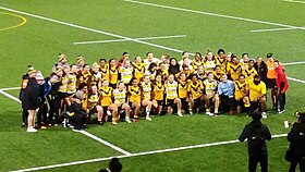 A group photo of two rugby league teams on a sports field