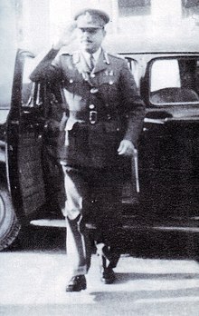 Ayub Khan en uniforme sort d'une voiture noire en faisant le salut militaire