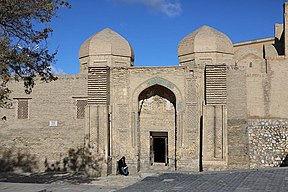 An entrance into a wall-like structure with two domes on top.