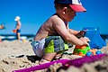 Image 28An infant boy playing with a toy dump truck at the beach. (from Boys' toys and games)