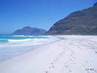 Looking north along the beach. The slopes of Chapman's Peak rise to the right at the end of the sand. The peak in the distance is Karbonkelberg, west of Hout Bay
