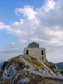 Two people walking away from a mountaintop chapel.