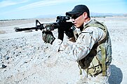 A US Navy SEAL aims his M4 carbine with an attached LA-5C/PEQ as part of the SOPMOD Kit.