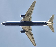 Vue de dessous d'un avion à réaction en vol. Un moteur est accroché à chacune des deux ailes. L’empennage horizontal est à l'arrière.