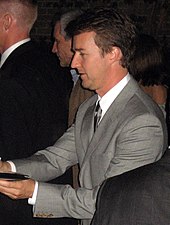 A side view of Norton in suits giving autographs