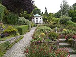 an octagonal gazebo in a woodland garden with stone paths