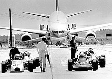 Un avion vu de face sur une piste de voitures de course.