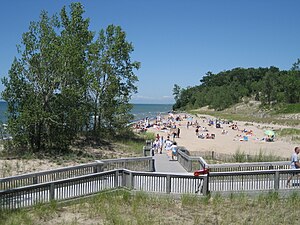 Photograph showing a sandy beach with sunbathers and Lake Ontario in the distance.