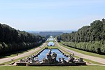 A large park with a pond in the middle, a palace at the far end