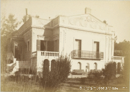 Photographie ancienne d'une villa avec façades moulurées, fronton triangulaire, balcon et parc.