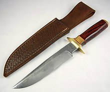 Large knife with polished wooden handle, lying next to a leather sheath