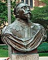 A copper bust of King Gustav Adolph's shoulders and head. He wears his military garb and a crown of laurels. His eyes are fixed at a point in the sky and his chin tilts upward confidently. He wears a full mustache and a triangular goatee. The bust is from Gustavus Adolphus College in Minnesota.