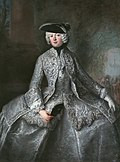 Fornemme kvinner kunne av og til bære «feminiserte» herreplagg i sin rokokkomote. Bildet viser prinsesse Anna Amalie av Preussen (1723-1787) kledt som amasone med justaucorps og trekanthatt, klar til et «fritt frilufts- og krigerliv», Maleri av hoffmaleren Antoine Pesne.