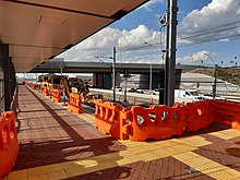 Brick paltform with construction barriers and machinery on tracks indicating platform is under construction