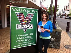 A vegan activist gives out baking by a World Vegan Day street poster