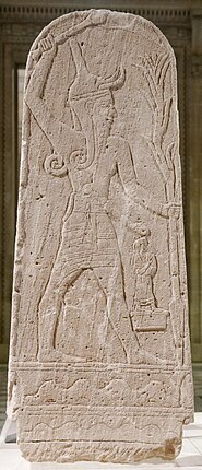 מצבת אבן (Baal au foudre) מאוגרית המתארת את בעל חובש כובע גבוה, מקורנן, עם שיער וזקן ארוכים, חגור חרב, מניף בימינו אלה ובשמאלו אוחז חנית ברק