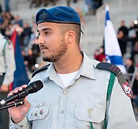 קצין במדי א', חובש כומתה כחולה עם סמל קטן בצבע מושחר הסטנדרטי של החיל.