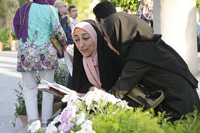 Una donna legge le poesie di Hafez accanto alla tomba