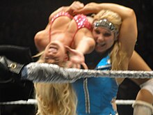 Beth Phoenix porte une catcheuse sur une épaule.