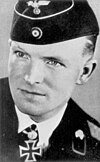 A black-and-white photograph of a man wearing a military uniform, side cap and a neck order in shape of an Iron Cross.