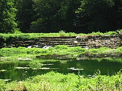 Photo montrant un grand barrage fait de grosses pierres de taille montées en gradins.