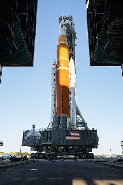 Le lanceur, sur sa table de lancement flanqué par la tour de service, quitte le VAB pour le pas de tir lors d'une répétition de lancement (mars 2022).