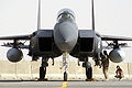 F-15E od przodu. Widoczny LANTIRN, zbiorniki paliwa pod skrzydłami, pociski AIM-120 (z białą głowicą) i AIM-9. Technik pracuje przy zamontowanych pod zbiornikiem konforemnym bombach GBU-12
