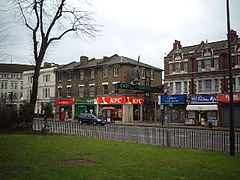 Street with row of shops one of which has a black cat sculpture above its entrance