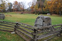 Log fence around a grassy field with fall-colored trees in background