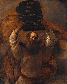 This is an image of an oil on canvas picture by Rembrandt (1659) of a bearded man representing Moses with two tablets of stone of the ten commandments held high in both hands.