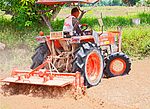 Jordfräs kopplad till en traktor under arbete på ett thailändskt risfält.