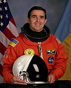 Leonid Kadenyuk di NASA, perhatikan warna biru yang berbeza pada patch dan di bendera di belakang (1997)
