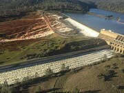 De Oroville Dam in februari 2017. Op de voorgrond de betonnen overlaat en daarachter stroomt het water over de snel eroderende noodoverlaat.