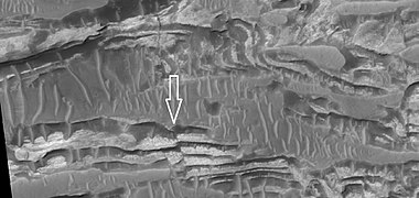 Close view of layers in Crommelin crater, as seen by HiRISE. Arrow points to a fault.