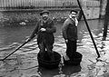 Deux hommes naviguant dans l'avenue dans des baquets en guise de barque.