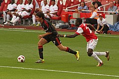 A colour photograph of Milan footballer Alexandre Pato on the ball, chased by opponent Emmanuel Eboué.