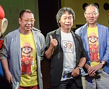 Trois hommes d'une cinquantaine d'années, micros en main, portant des t-shirts rendant hommage au personnage de Mario.