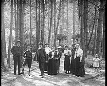 Photograph of participants in a game of boules in the Rambouillet woods. Ten people, including six women, two men and two children pose.