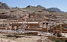 vue éloignées extérieures de ruines avec des escalier, des colonnades. Quelques personnes marchent dans le temple.